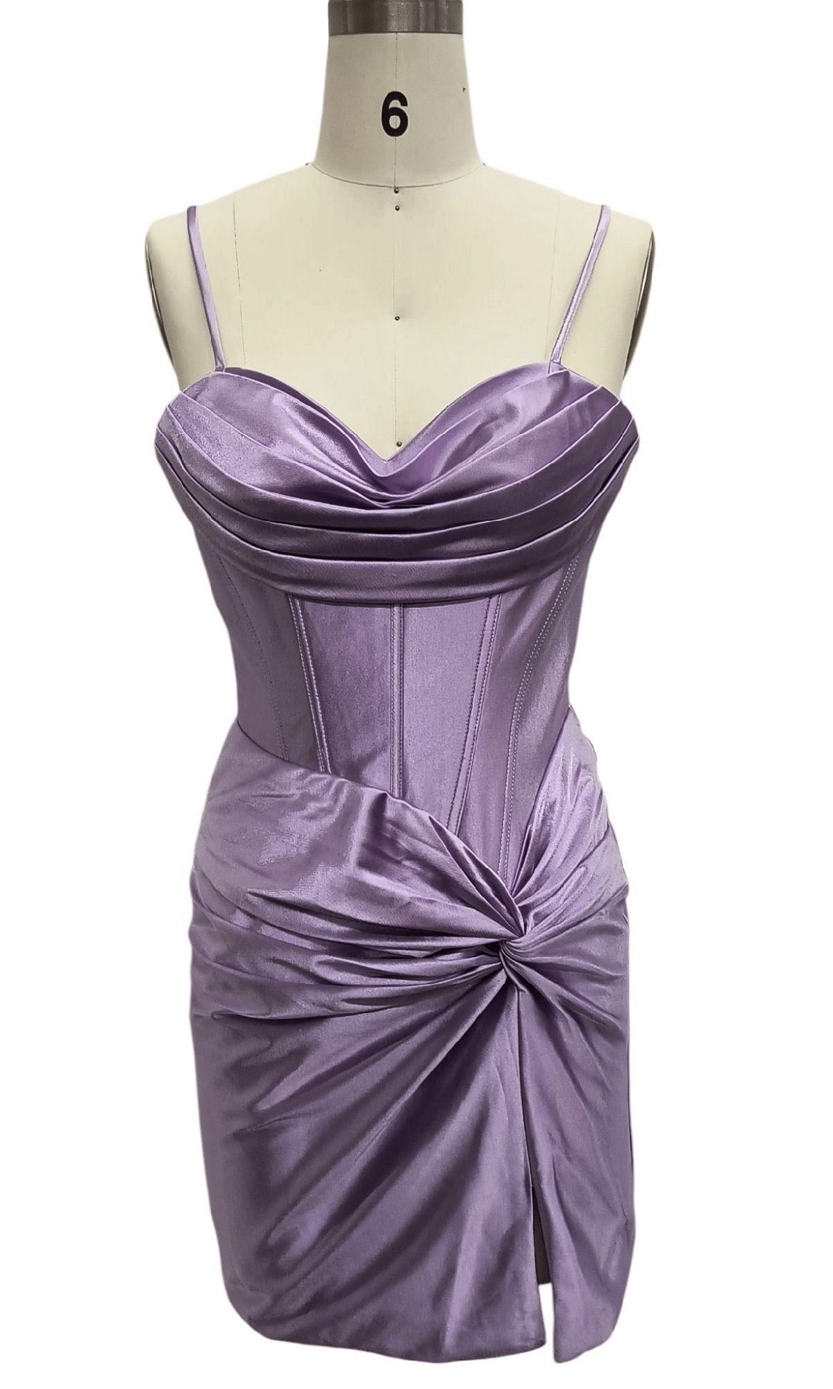 The Short Lilac Corset Hoco Dress: 12623 features lilac satin, spaghetti straps, a pleated sweetheart neckline, ruched waist, and front slit. Shown on a dress form labeled 6, this flirty mini is perfect for homecoming.